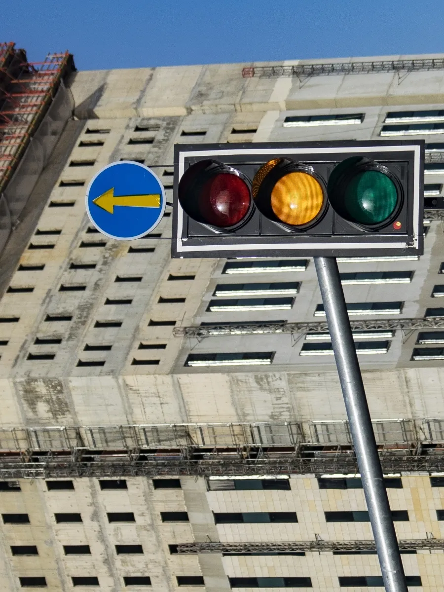 Traffic light and blue arrow sign in front of a concrete building facade